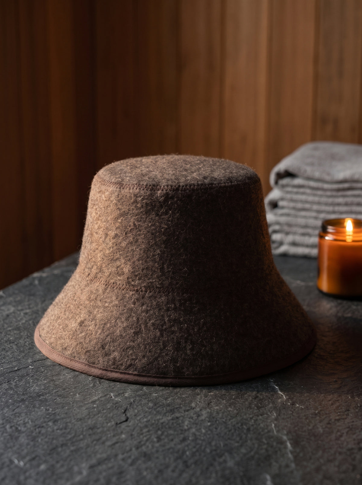 G0-urun-slate | The Montelani sauna hat in dark brown 100% wool felt on a slate stone