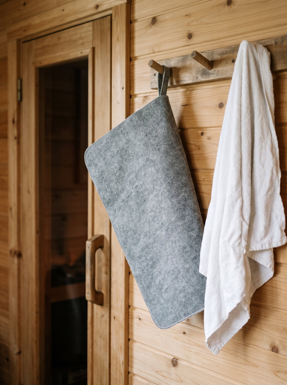 Seat pad hanging by its loop on a peg next to a towel